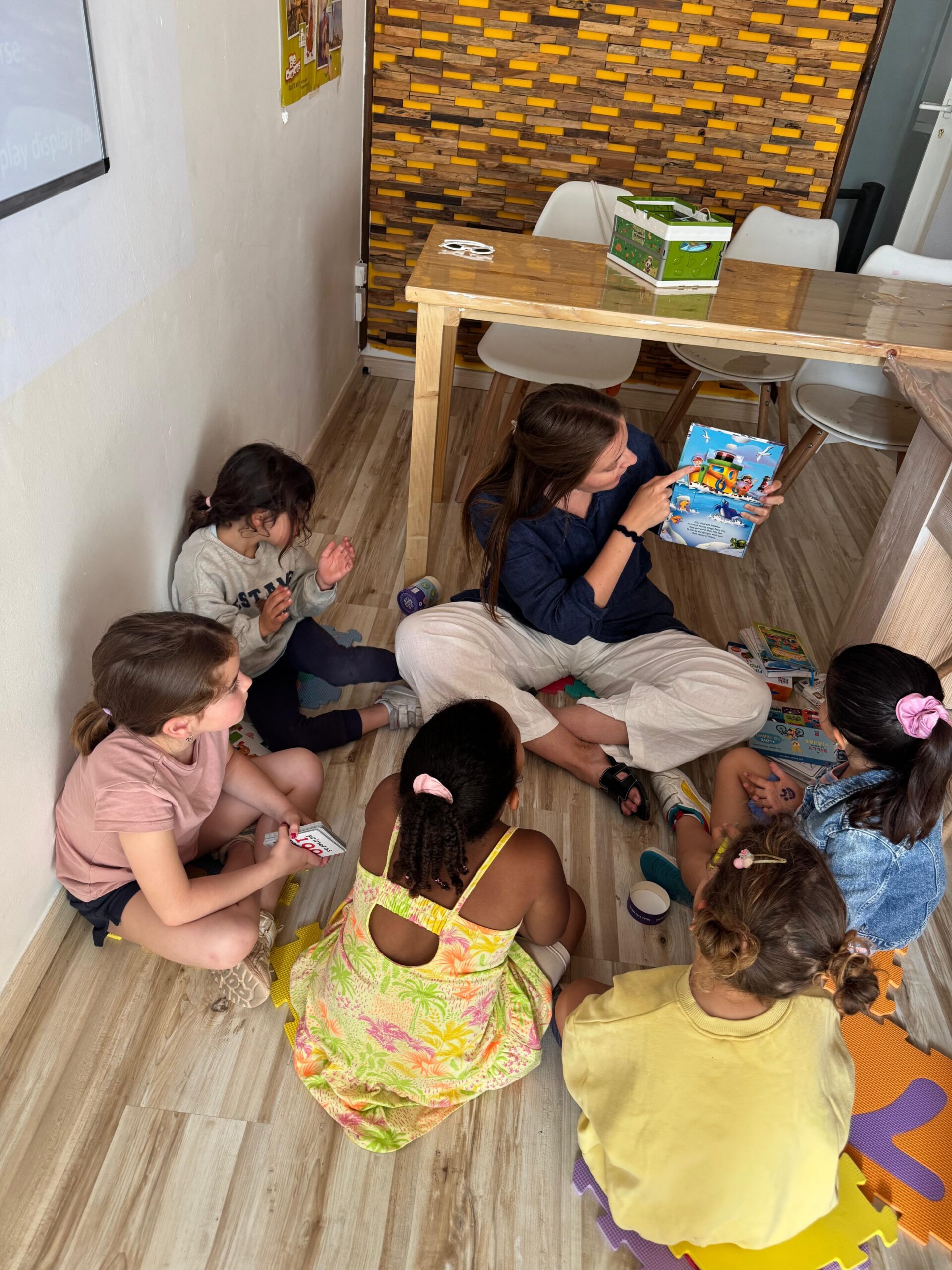Profesora leyendo con alumnos sentados en el suelo